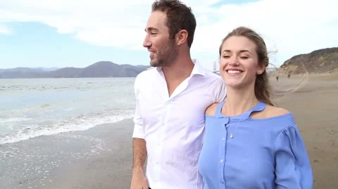 Cute couple walking down beach towards camera talking Stock Footage 41969708