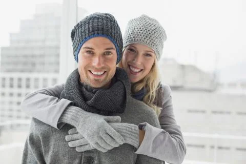 Cute couple in warm clothing hugging smiling at camera Stock Photos