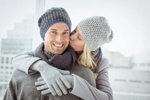 Cute couple in warm clothing hugging man smiling at camera Stock Photos
