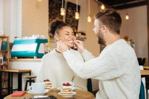 Cute couple wearing the same sweaters eating delicious desserts Fotos Stock