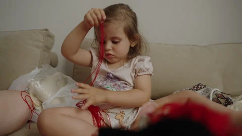 Cute creative little gir playing with needles and ribbons in a white sunny room Stock Footage 256924513