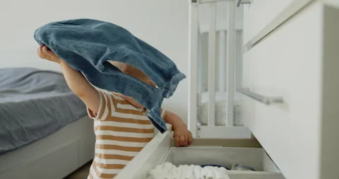 Cute curious toddler pulls things out of a dresser drawer Stock Footage 304658045