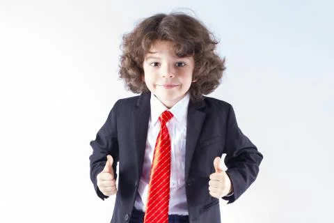Cute curly boy in an unbuttoned jacket looking at the camera and showing hand Stock Photos