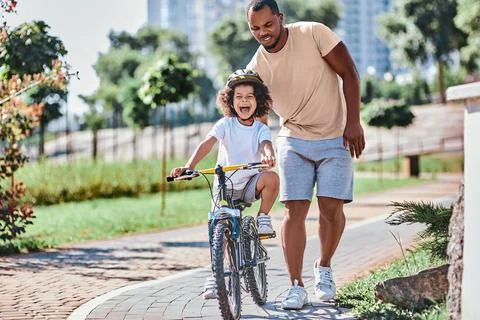 Cute curly kid learning how to ride a bike Stock Photos