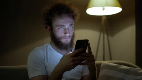 Cute curly young man writes texting online using smartphone. Business Stock Footage 160968301