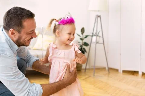 Cute daughter with magic wand playing with father Stock Photos