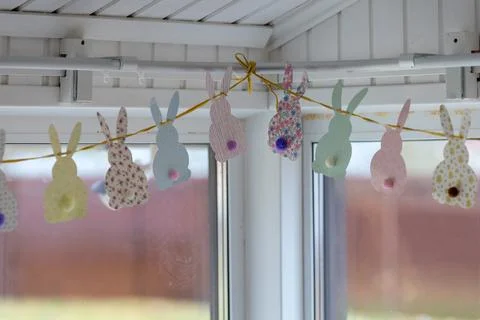 Cute Easter bunnies made of paper with yarn tails with pompoms. Stock Photos