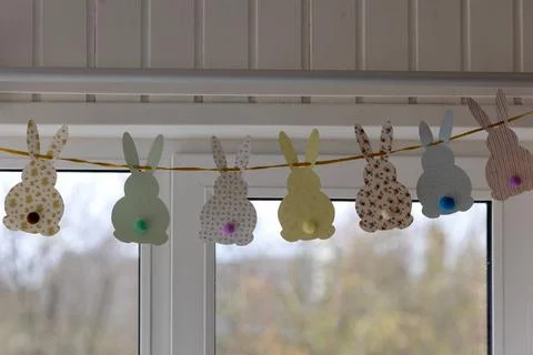 Cute Easter bunnies made of paper with yarn tails with pompoms. Stock Photos