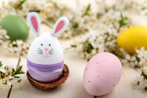 Cute Easter bunny, eggs and a plum flowers on wooden background Stock Photos