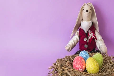 Cute Easter bunny with painted eggs and a place for text on lavender backgrou 写真素材