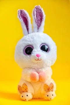 Cute easter bunny rabbit plush doll sitting on yellow background. Stock Photos