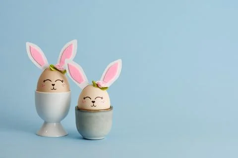 Cute Easter bunny shaped eggs in egg holders on blue background. Place for yo 스톡 사진