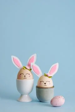 Cute Easter eggs bunny in egg holders on blue background. Vertical postcard.  Stock Photos