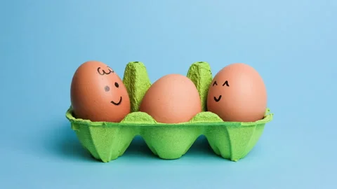 Cute easter eggs with funny faces in green box isolated on blue background Stock Footage 235897577