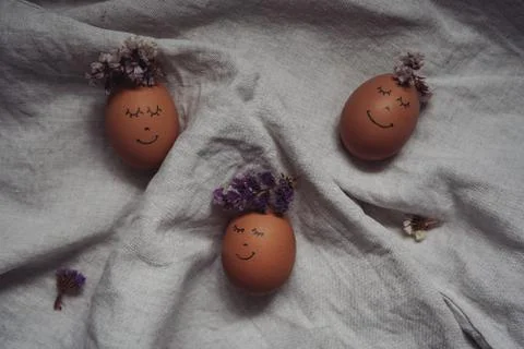 Cute Easter eggs with a painted face with a flower wreath on the linen cloth Stock Photos