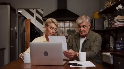 Cute elderly couple sitting in kitchen sorting through documents Stock Footage 170897997