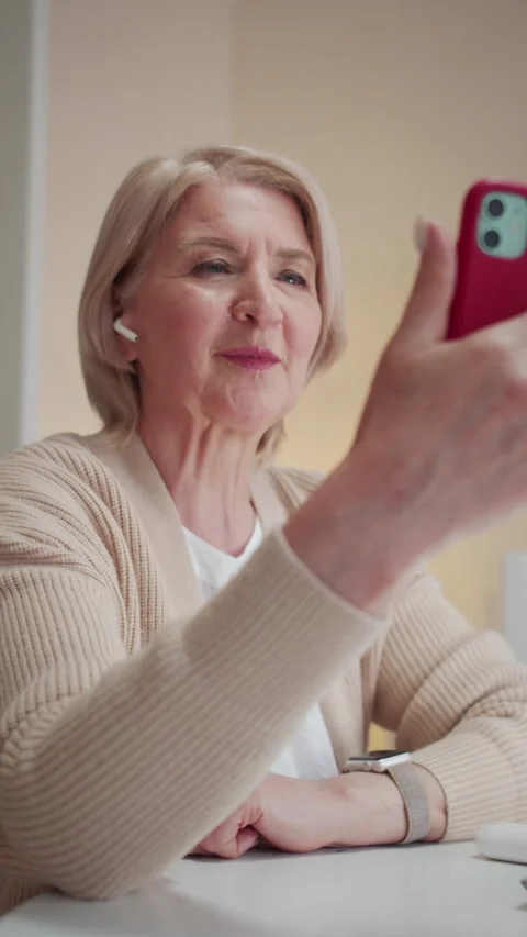 A cute elderly woman is using a video call on a smartphone. She waves her hand Stock Footage 173571872