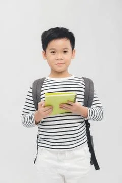 Cute elementary school boy holding books on white background Stock Photos