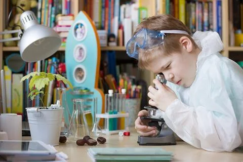 Cute elementary school boy looking into microscope at his desk at home. Young Stock Photos