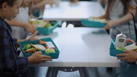 Cute elementary school children sitting by table eating their tasty snacks Stock Footage 111970643