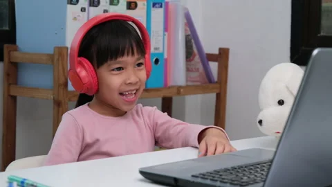 Cute elementary school girl wearing headphones and using a laptop computer. Stock Footage 235791908