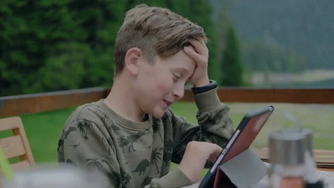 Cute exited boy plays with tablet while sitting outdoor. Stock Footage 138738893