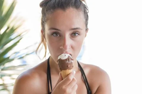 Cute face of a lady looking the camera holding and eating an ice cream Stock Photos