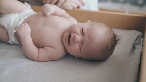 Cute fair haired newborn boy lies on baby table and cries Stock-Footage 113462880
