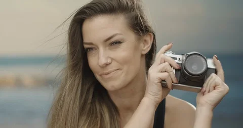 Cute female photographer using her analogue camera at the beach. Sea in the Stock Footage 122914079