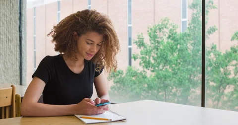 Cute female student texting while working on homework 4k Video stock 49683622