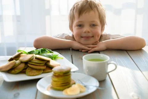 Cute five year boy with stack of spinach pancakes Foto stock