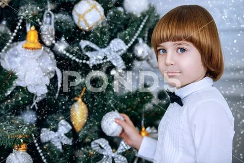 Cute five-year-old boy in elegant evening clothes, decorates the Christmas tr Stock Photos