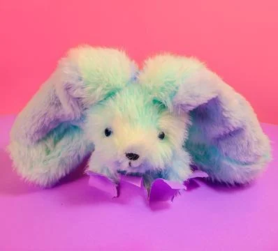 Cute fluffy Easter bunny peeping out of purple torn paper 库存照片