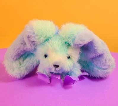 Cute fluffy Easter bunny peeping out of purple torn paper Foto stock