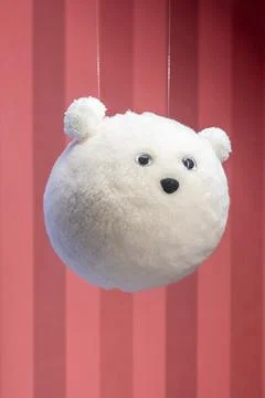 Cute fluffy white teddy bear toy hanging on pink background 库存照片