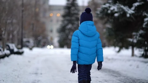 Cute four years old boy in blue winter clothes walks in snowy street Stock Footage 122535638
