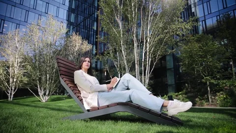 Cute freelancer working on nature sitting with notepad. Looking for inspiration Stock Footage 262142487