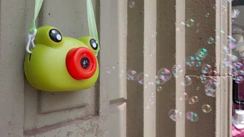 Cute frog-shaped bubble machine attached to wall blowing bubbles, camera fixed 動画素材 313478826