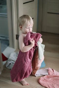Cute funny baby playing with stack of towels in the bathroom at home Stock Photos