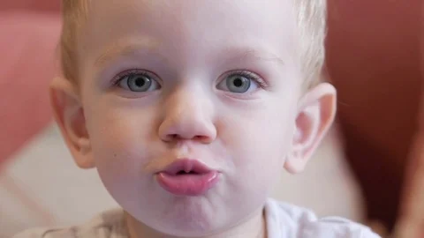 Cute funny boy pulls his lips and laughs. Home decor in the background. Close-up Video stock 81237839
