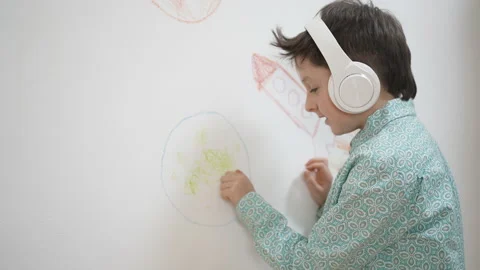Cute funny school child boy artist in headphones drawing coloring picture with Stock Footage 168862479