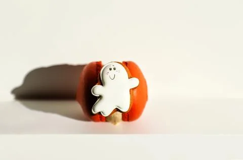 Cute ghost gingerbread cookie on top of an orange macaron. Halloween themed.. Foto stock