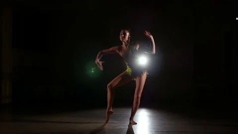 Cute girl athlete performs elements of rhythmic gymnastics in dark gym Stock Footage 104689529