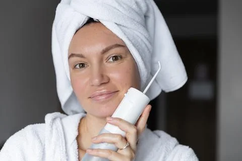 Cute girl in bathrobe with irrigator, teeth cleaning concept and caries Stock Photos