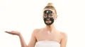 The cute girl with a black face care mask gesturing on the white background 4k or 4k+ Resolution