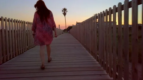 Cute girl comming back from the beach at sunset Stock Footage 133523809