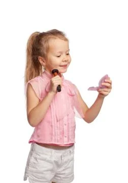 Cute girl does makeup using lip gloss, looking in a small hand mirror Stock Photos