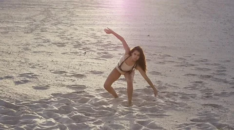 Cute girl doing impromptu dance moves on the sand at sunset Stock Footage 67487399