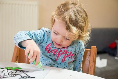 Cute girl drawing a fish using glass colors at home. Stock Photos