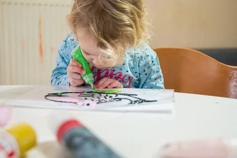Cute girl drawing a fish using glass colors at home. Stock Photos